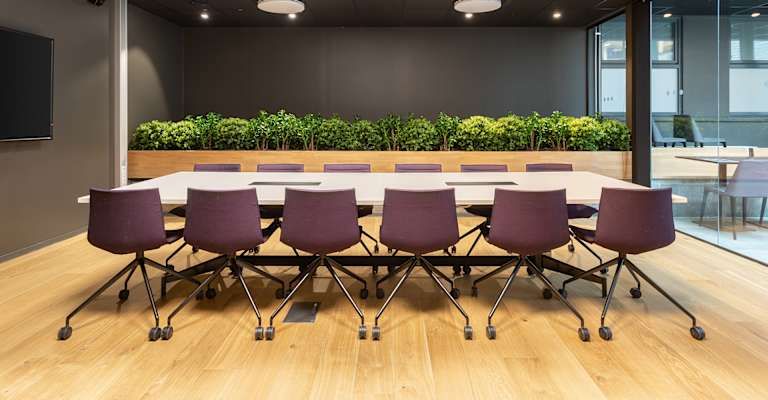 Modern konferensrum på Södermalm med lila stolar och gröna växter.
